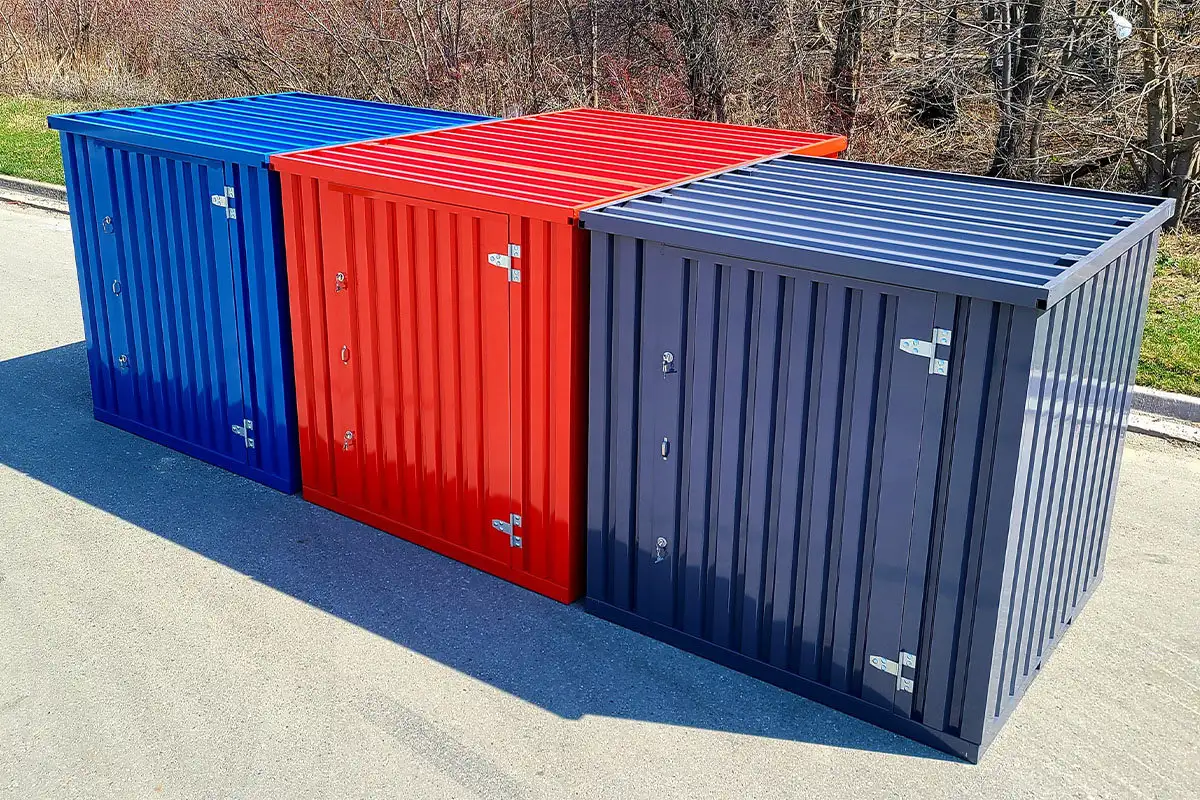 Row of Storage-Tech flat pack storage containers outdoors in red, blue and grey