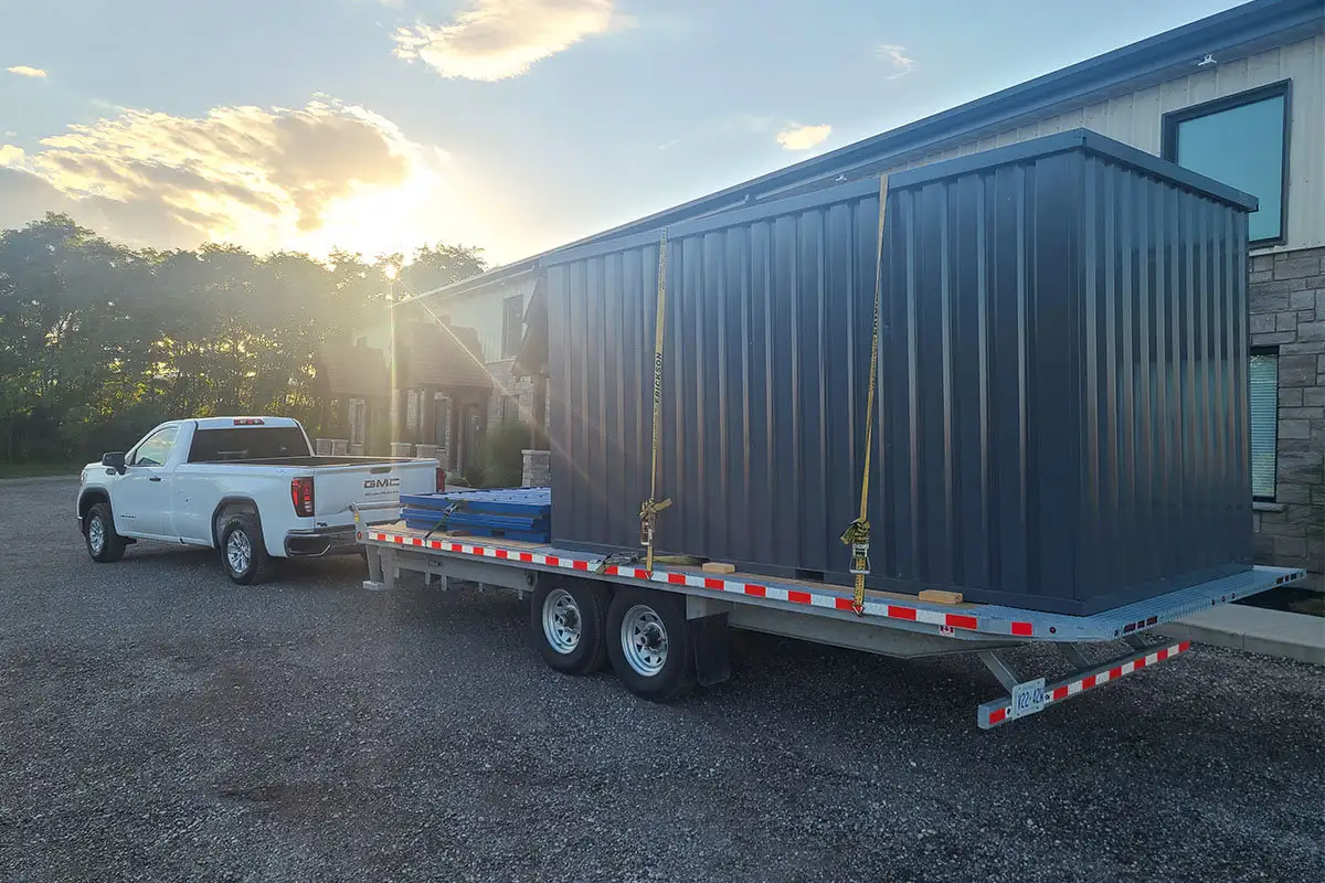 Dark grey Storage-Tech storage container being transported outdoors